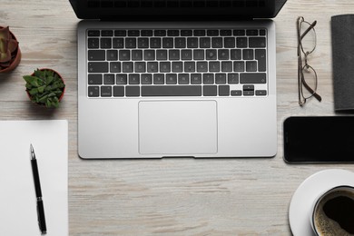 Modern laptop, houseplants, notebook, cup of coffee and glasses on wooden table, flat lay