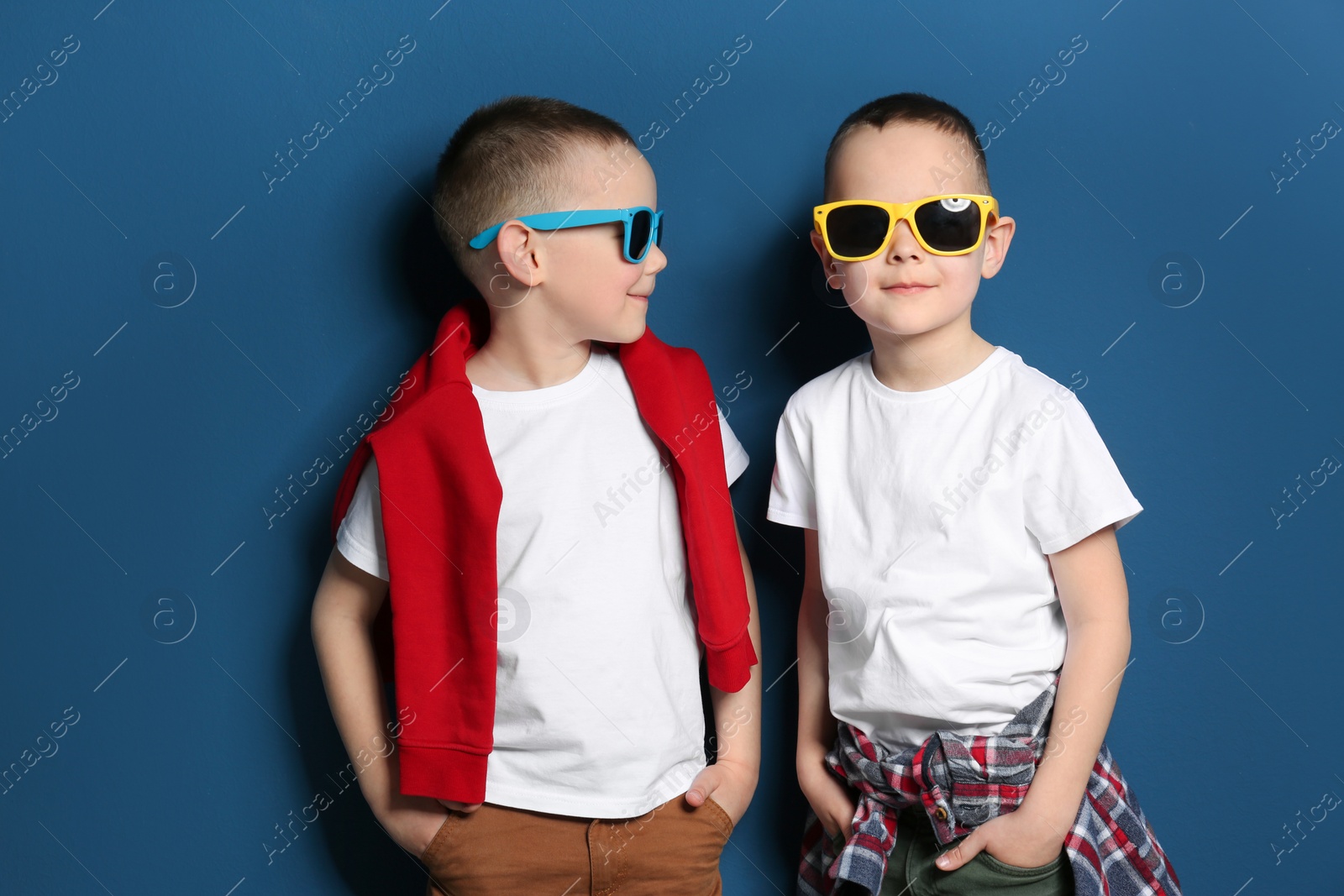 Photo of Portrait of cute twin brothers with sunglasses on color background