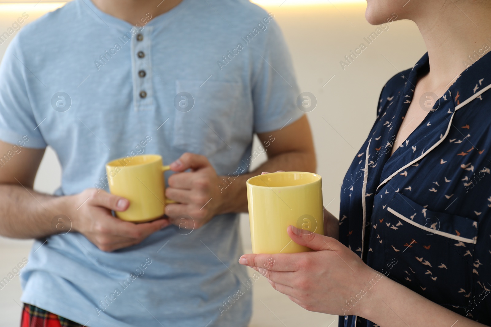 Photo of Couple in pajamas with mugs at home, closeup