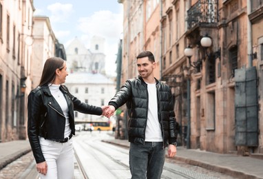 Photo of Lovely young couple walking along tram track on pavement road. Romantic date