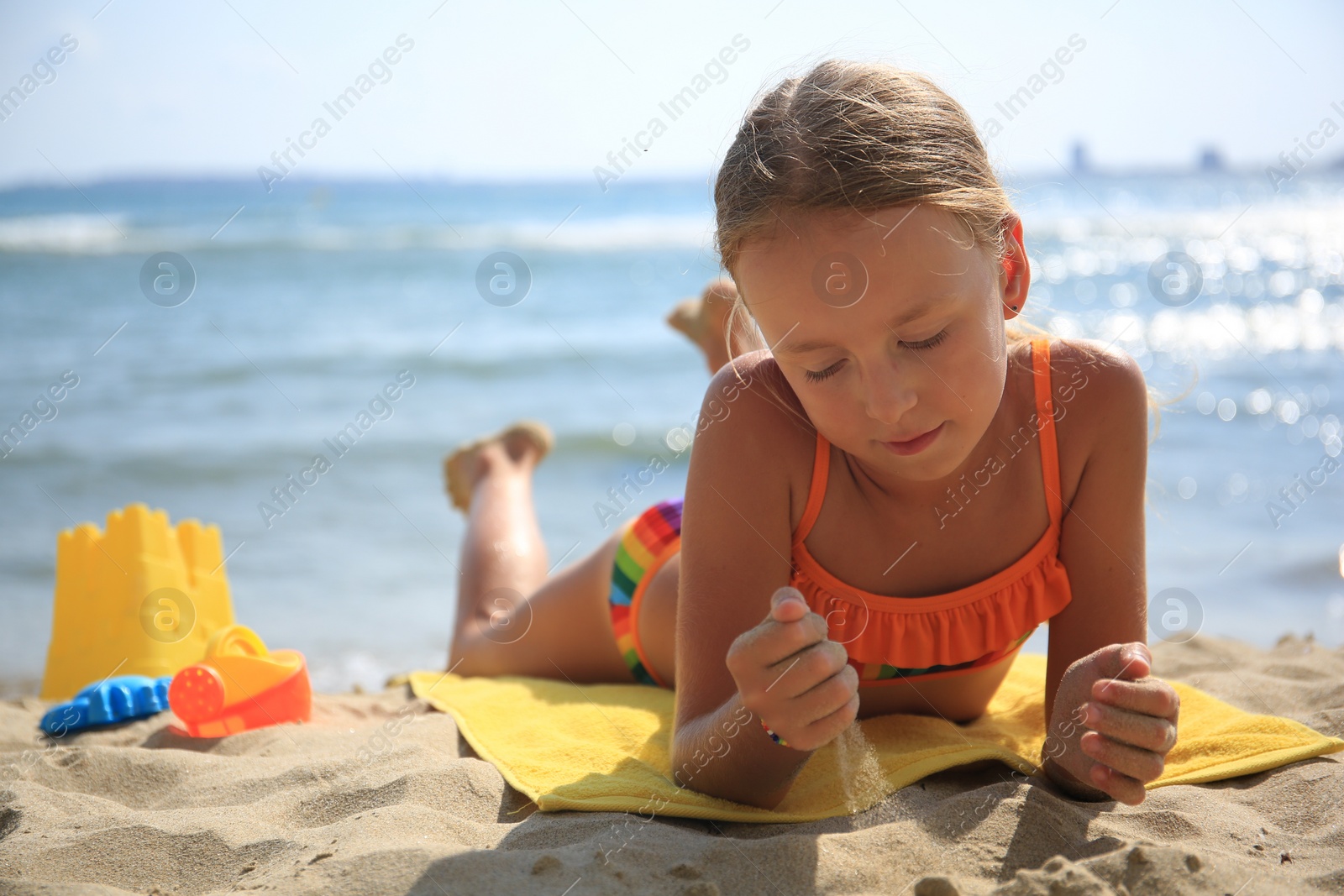 Photo of Little girl playing with sand on beach near sea. Space for text
