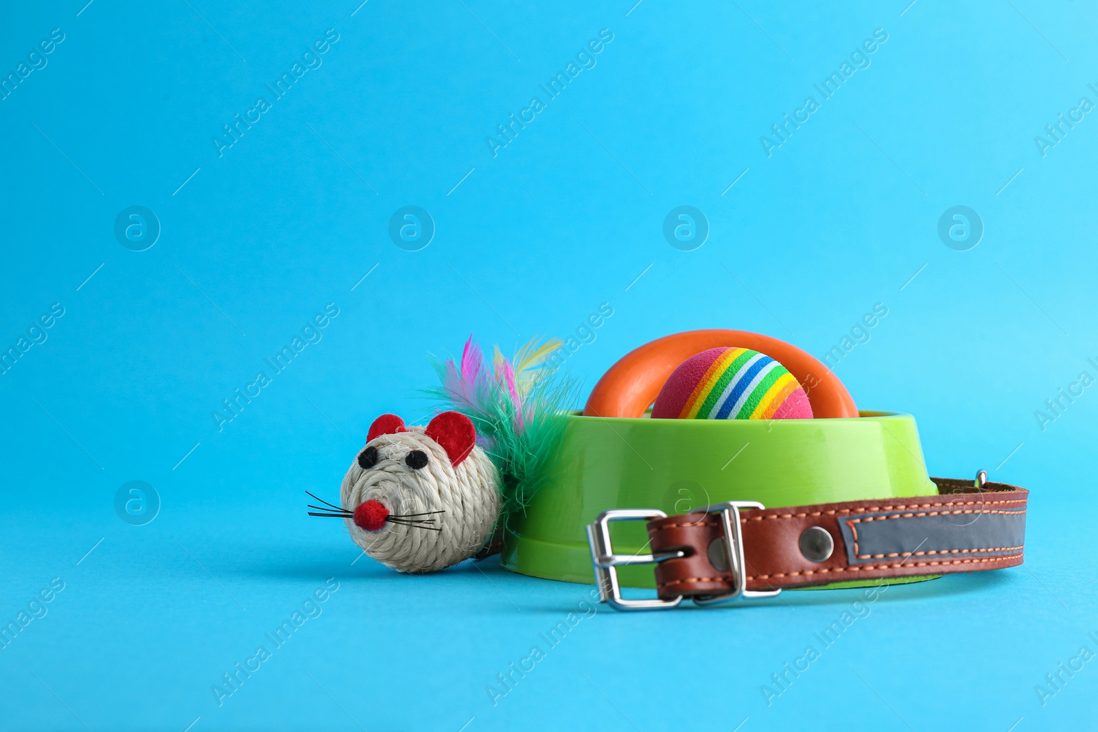 Photo of Pet toys, collar and feeding bowl on light blue background, space for text