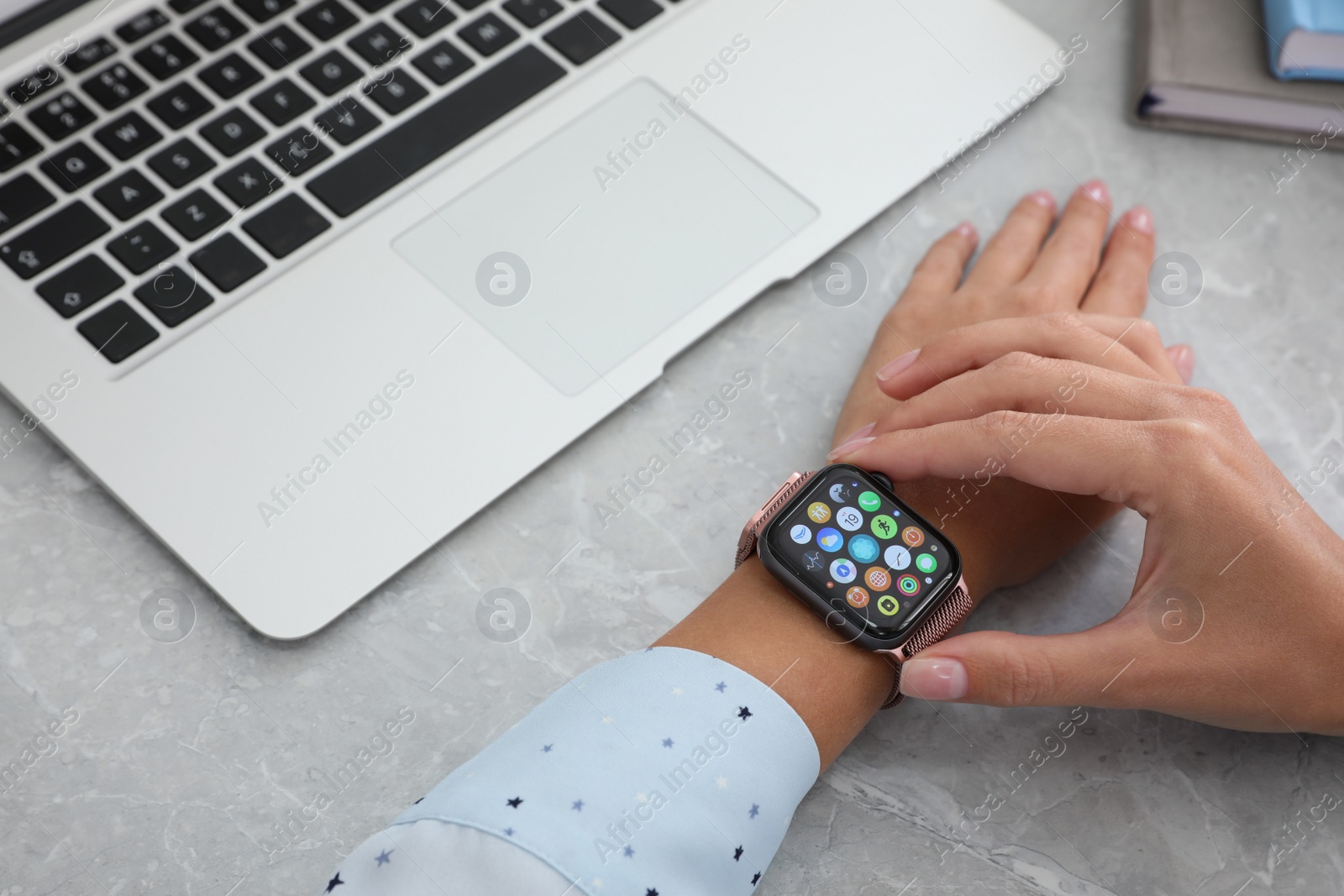 Image of MYKOLAIV, UKRAINE - SEPTEMBER 19, 2019: Woman using Apple Watch at grey table, closeup