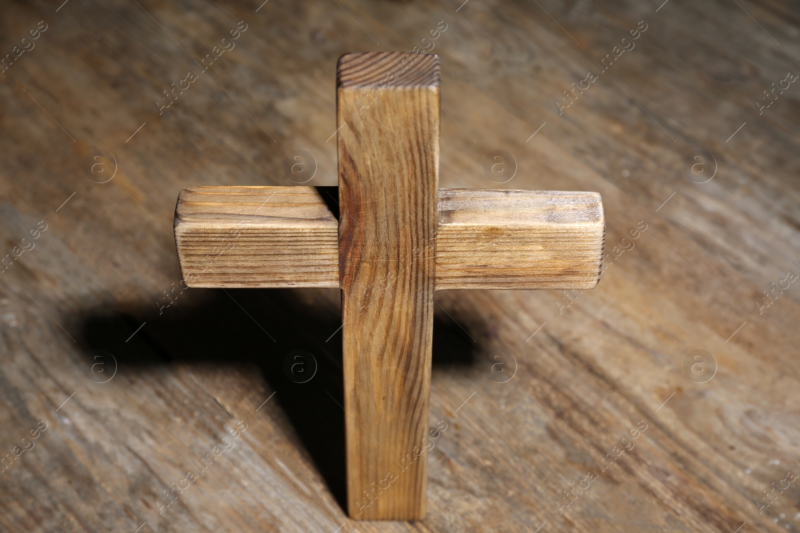 Photo of Christian cross on wooden background, above view. Religion concept