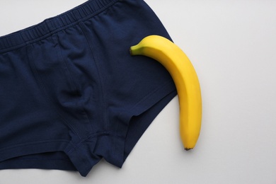 Photo of Men's underwear and banana on light background, flat lay. Potency problem concept