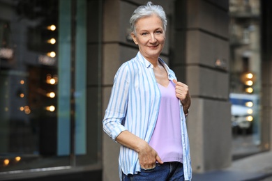 Photo of Happy mature woman on city street. Smart aging