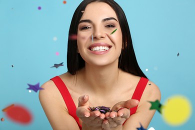 Photo of Happy woman and falling confetti on light blue background