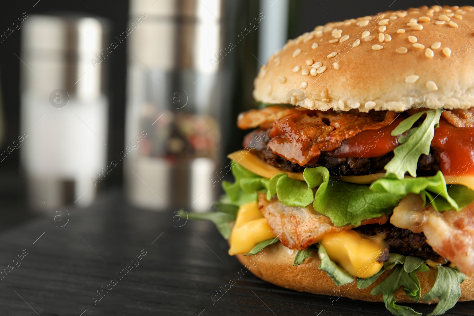 Photo of Tasty burger with bacon on board, closeup. Space for text