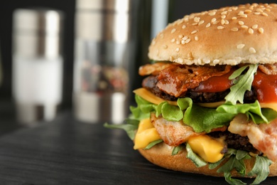 Tasty burger with bacon on board, closeup. Space for text