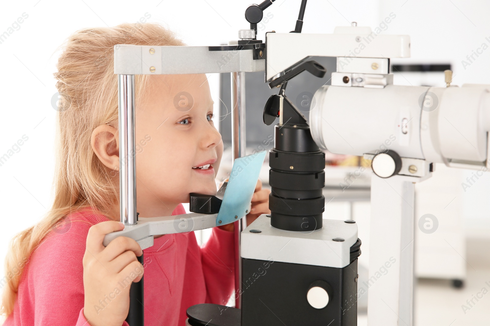 Photo of Little girl visiting children's doctor in clinic. Eye examination