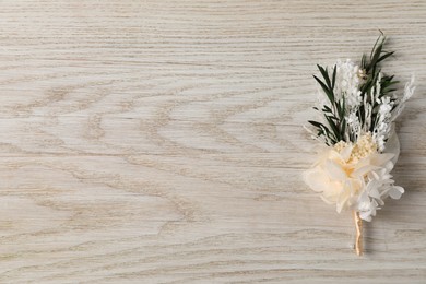Photo of Stylish boutonniere on white wooden table, top view. Space for text