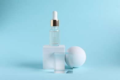 Stylish presentation of cosmetic serum on light blue background