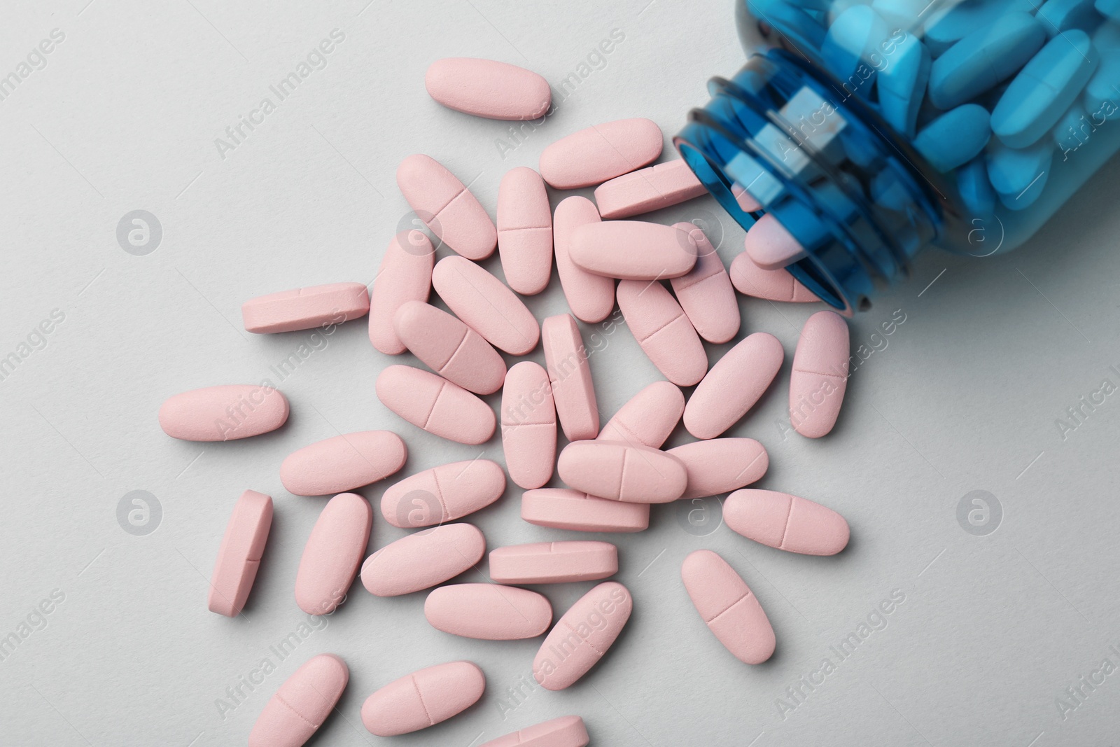 Photo of Vitamin pills and bottle on grey background, top view