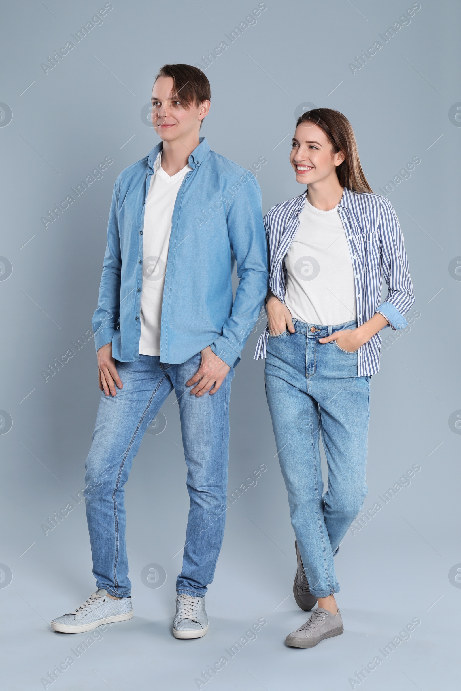 Photo of Young couple in stylish jeans on grey background