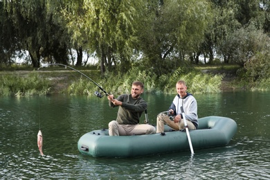 Photo of Friends fishing from boat on river. Recreational activity