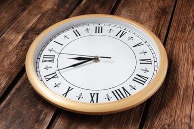 Photo of Clock showing five minutes until midnight on wooden table, closeup. New Year countdown