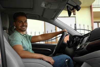 Handsome young man driving modern family car outdoors