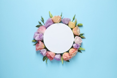 Flat lay composition with beautiful Eustoma flowers and card on light blue background, space for text