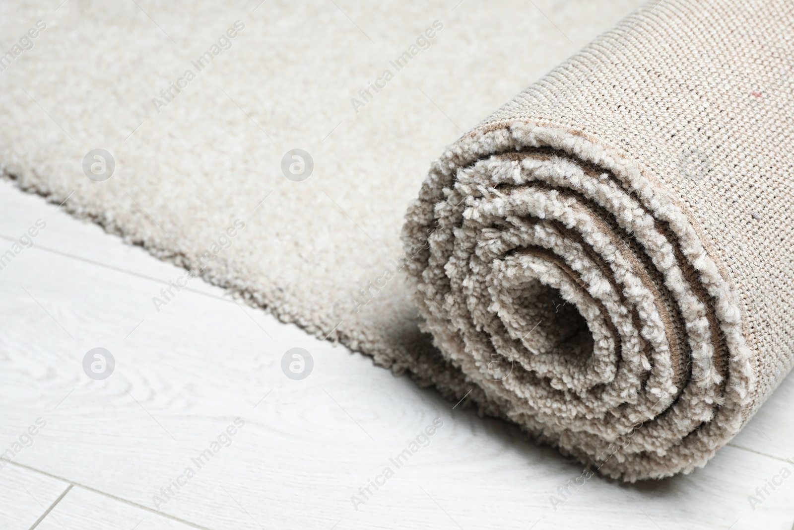 Photo of Rolled fuzzy carpet on wooden background, closeup. Space for text