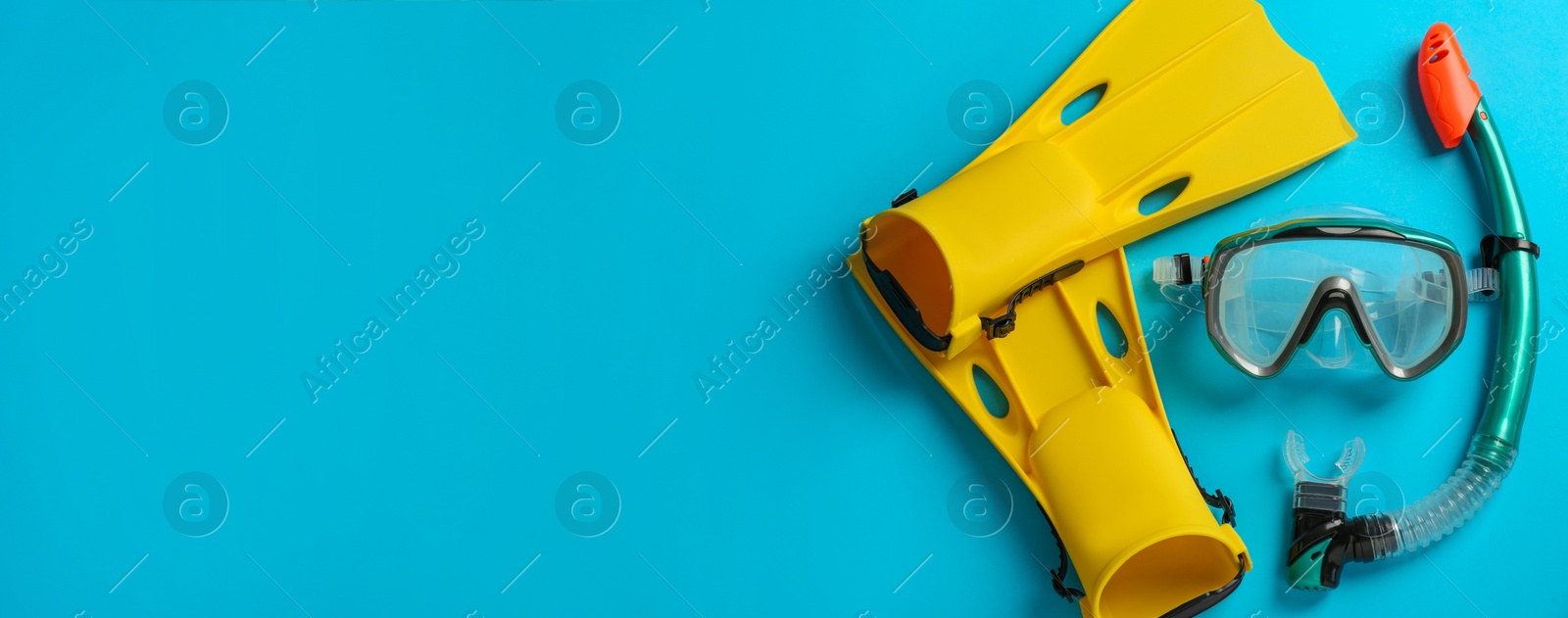 Photo of Pair of yellow flippers and mask on light blue background, flat lay