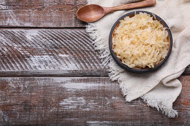 Photo of Bowl of tasty sauerkraut on wooden table, flat lay. Space for text