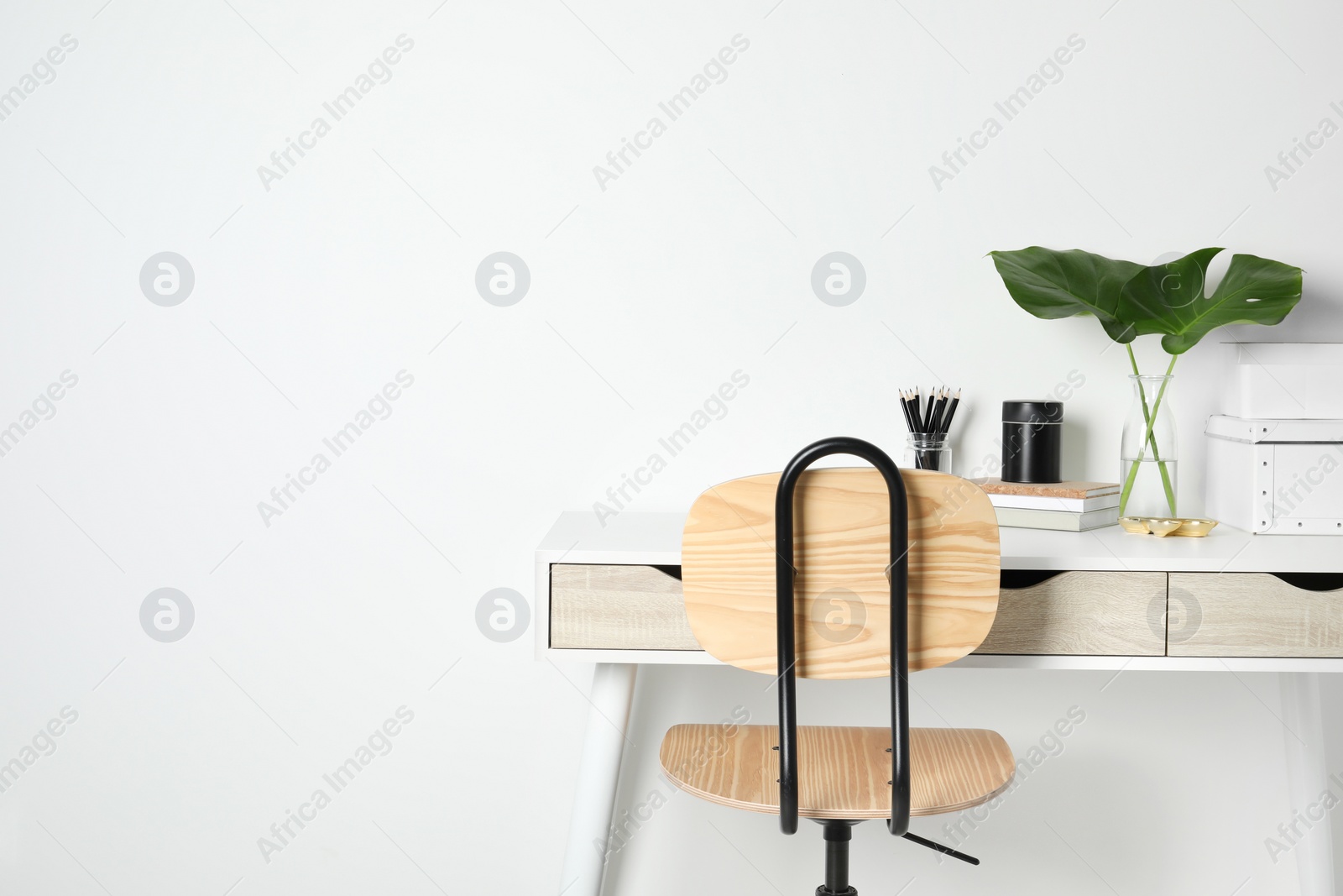 Photo of Comfortable workplace with white desk near wall. Space for text