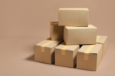 Photo of Stack of many cardboard boxes on light brown background, space for text