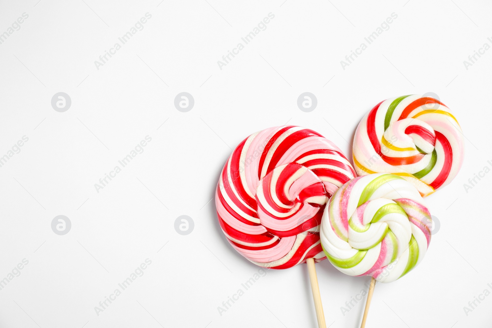 Photo of Sticks with colorful lollipops on white background, flat lay. Space for text