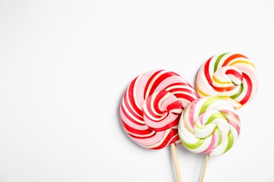 Sticks with colorful lollipops on white background, flat lay. Space for text