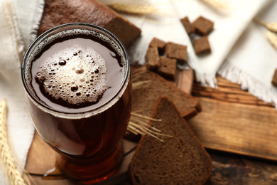 Photo of Glass of delicious kvass, spikes and bread on wooden table. Space for text