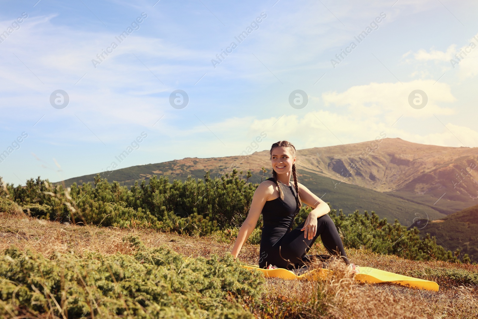 Photo of Beautiful young woman practicing yoga in mountains on summer morning
