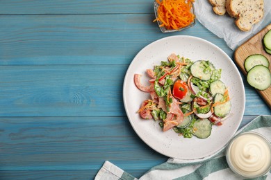 Photo of Plate of delicious vegetable salad with mayonnaise served on light blue wooden table, flat lay. Space for text