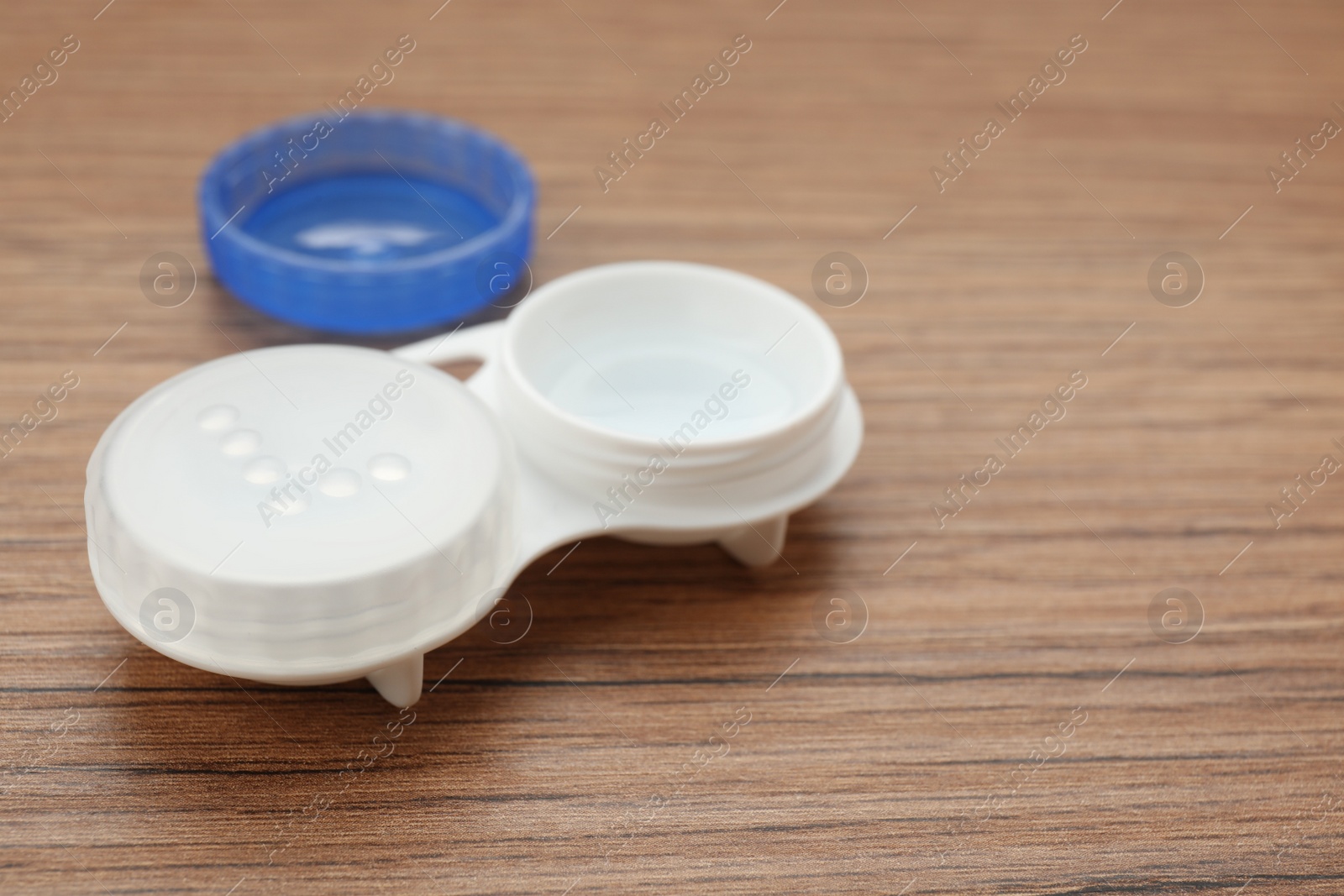 Photo of Case with contact lenses on wooden table, closeup. Space for text