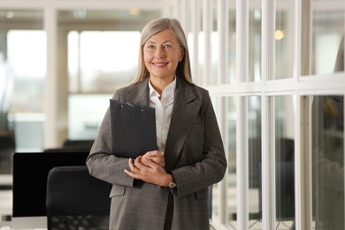 Photo of Smiling woman with clipboard in office. Lawyer, businesswoman, accountant or manager