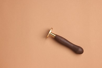 Photo of One stamp tool with wooden handle on light brown background, top view. Space for text