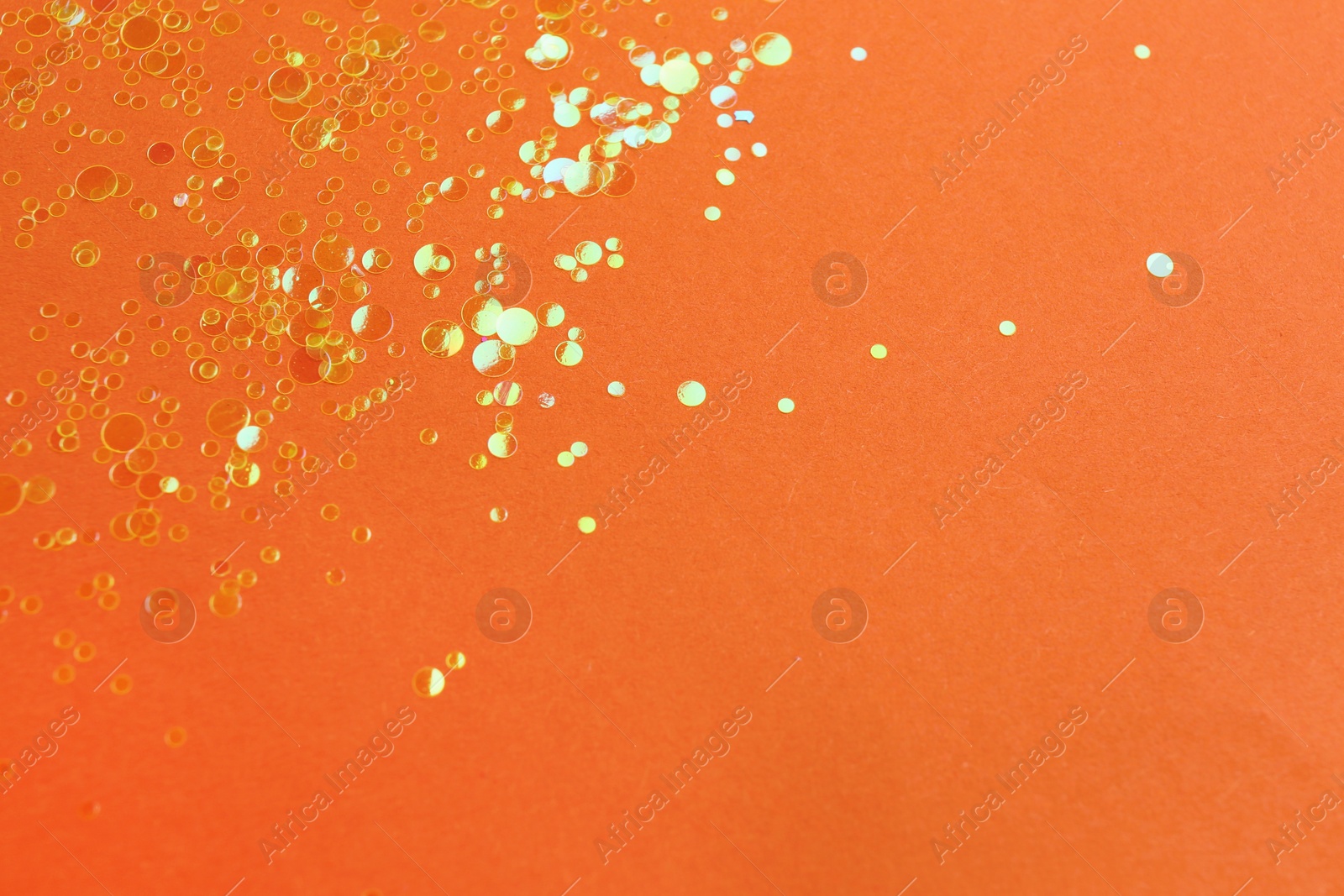 Photo of Shiny bright golden glitter on orange background. Space for text