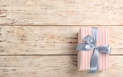 Elegant gift box with bow on wooden background, top view