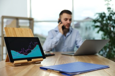 Photo of Broker working in office, focus on tablet with chart. Forex trading
