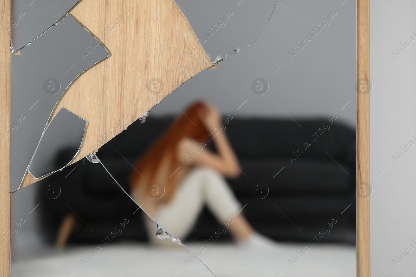 Photo of Mental problems. Blurred reflection of depressed woman in broken mirror