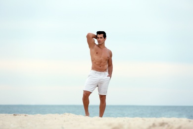 Photo of Handsome young man posing on beach near sea