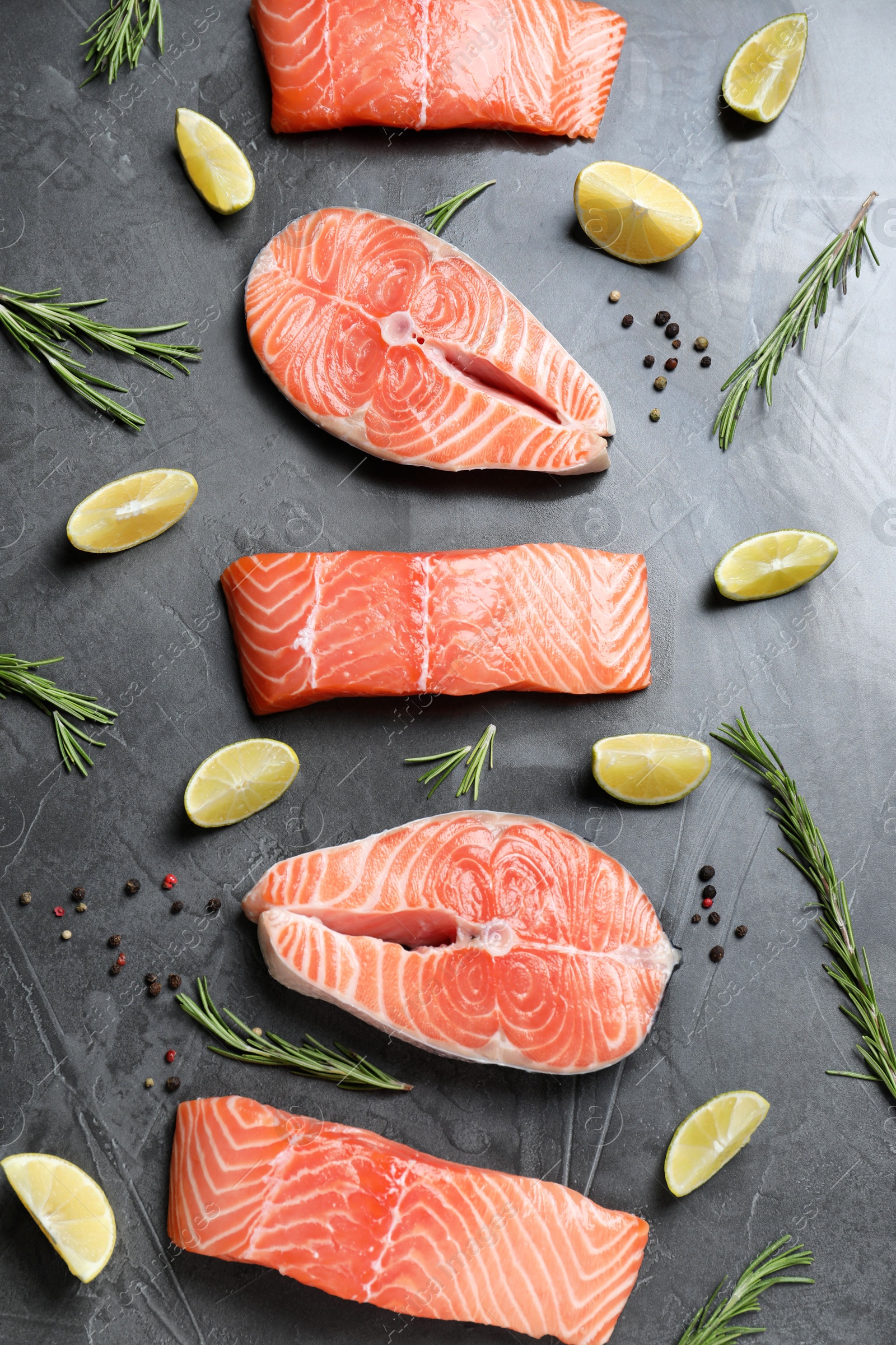 Photo of Flat lay composition with fresh raw salmon, rosemary and lemon on dark grey table. Fish delicacy