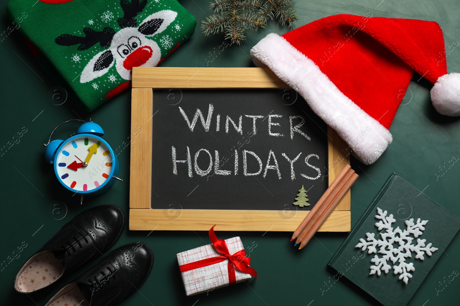 Photo of Blackboard with text Winter Holidays and Christmas decor on green background, flat lay