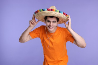 Photo of Young man in Mexican sombrero hat on violet background