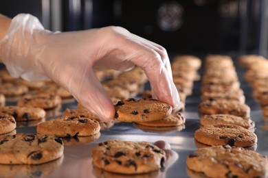 Photo of Woman taking delicious cookie from production line, closeup