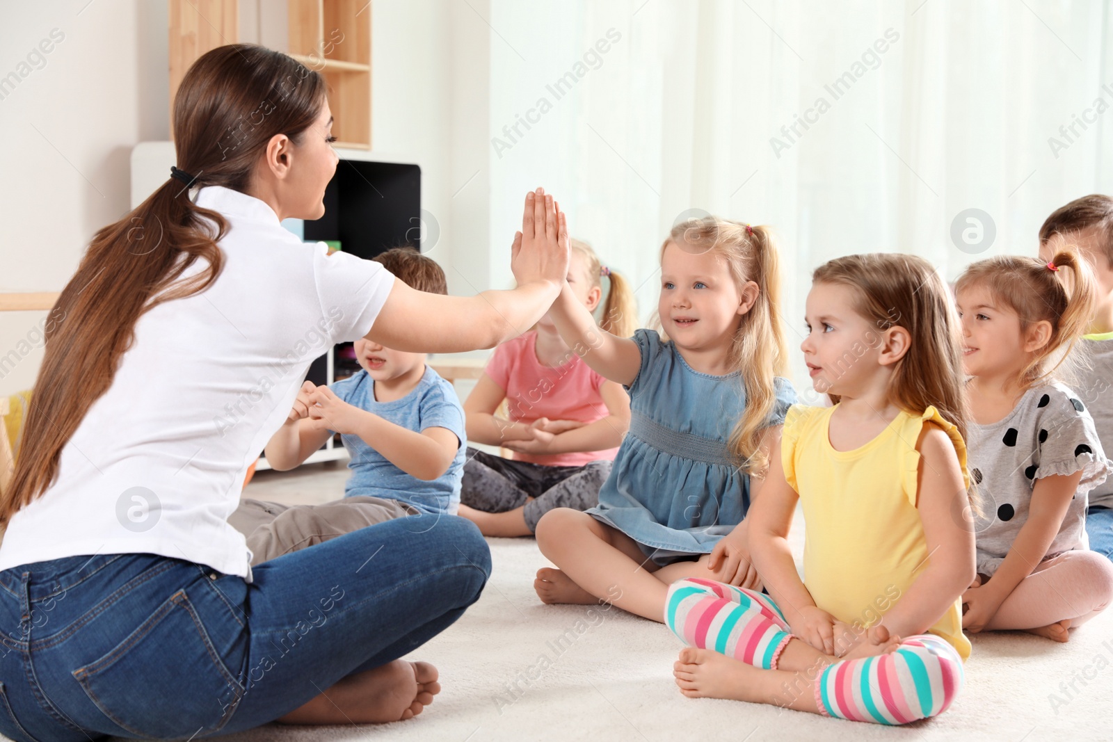 Photo of Kindergarten teacher and little children indoors. Learning and playing