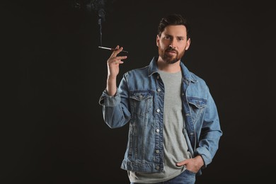 Photo of Man using cigarette holder for smoking on black background, space for text