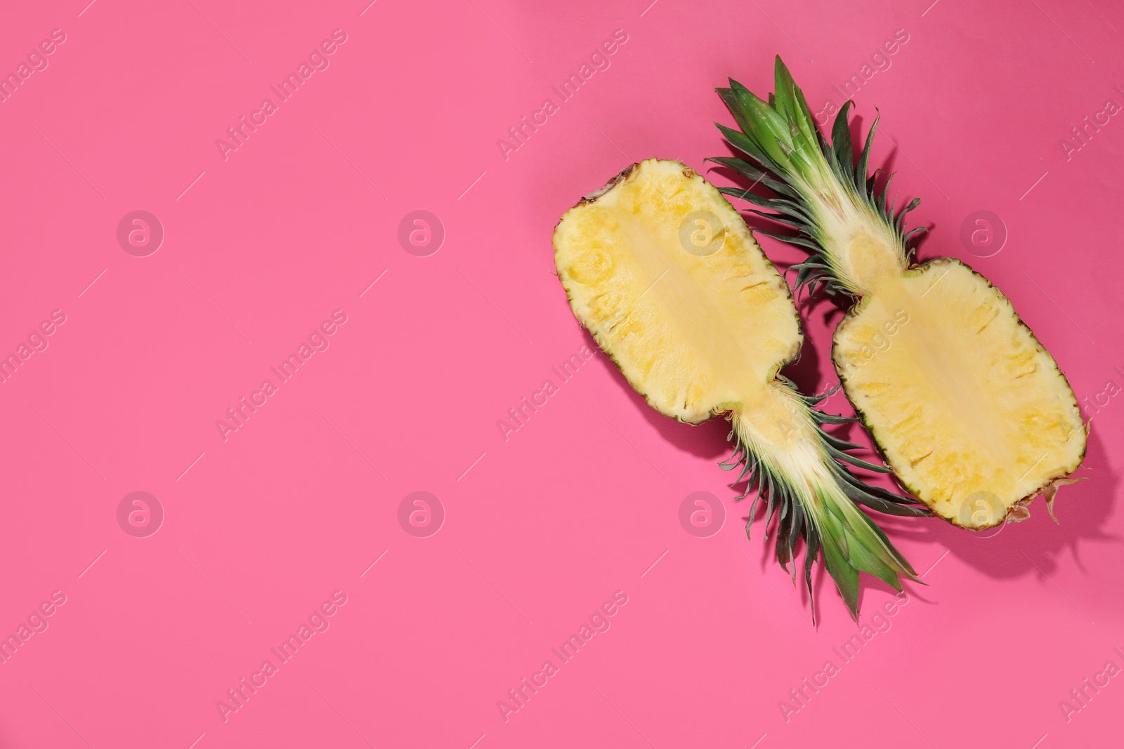 Photo of Halves of ripe pineapple on pink background, flat lay. Space for text