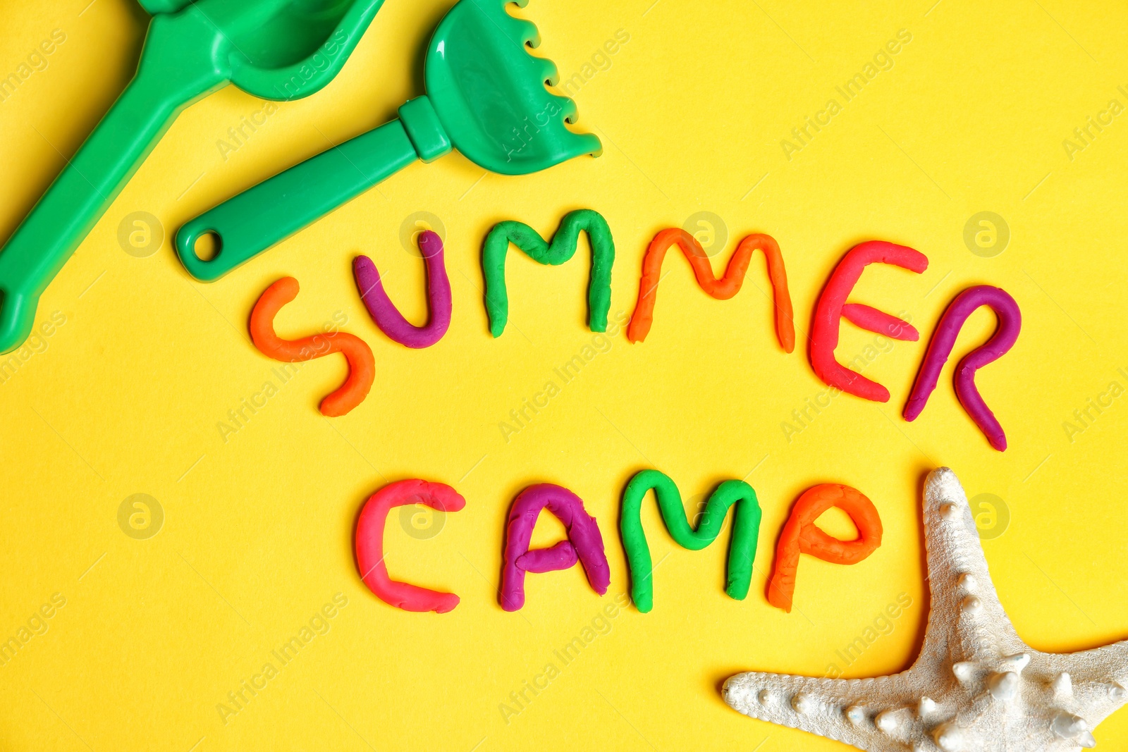 Photo of Flat lay composition with words SUMMER CAMP made from modelling clay and beach toys on color background