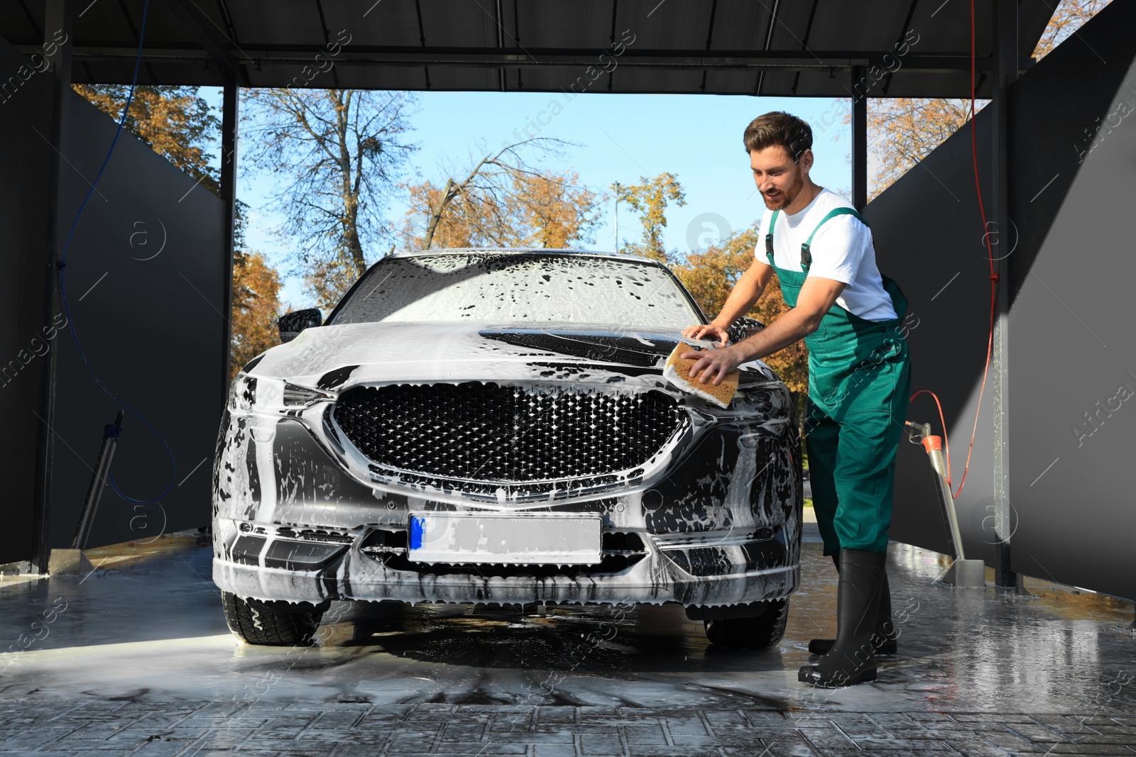 Photo of Worker washing auto with sponge at outdoor car wash