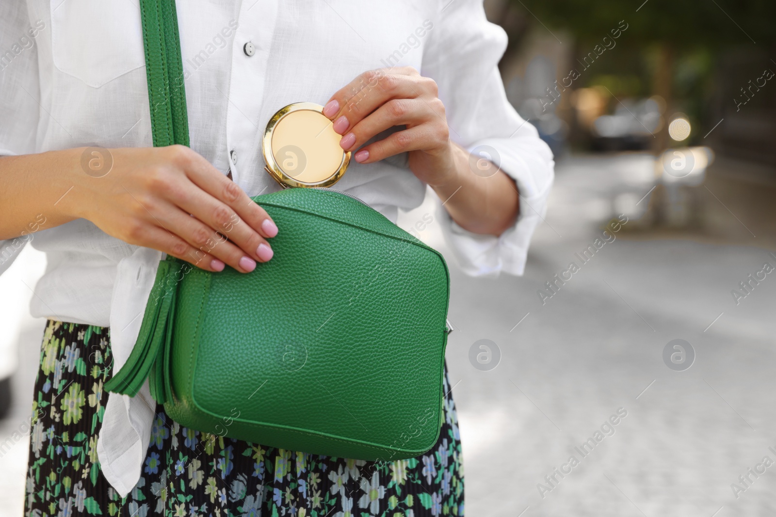 Photo of Woman taking cosmetic pocket mirror from bag outdoors, closeup